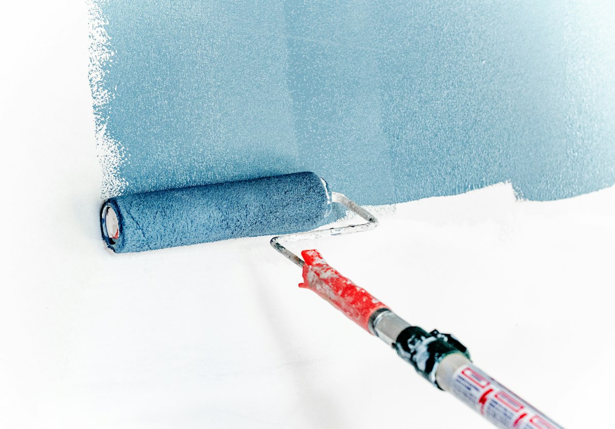 Rouleau appliquant de la peinture bleue sur un mur blanc